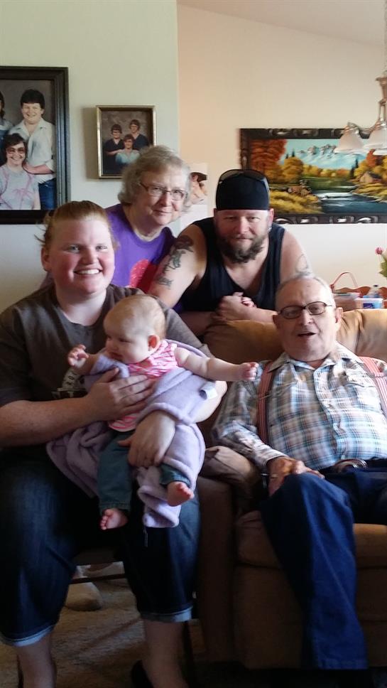 A loving family gathers, enjoying time with infants and elders in a cozy living room.