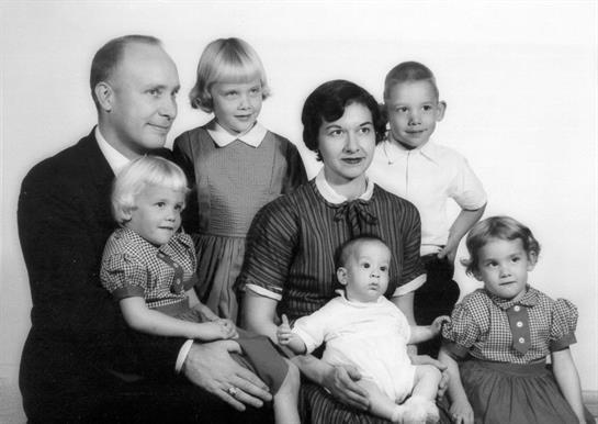 A family gathers for a studio portrait, smiling and showcasing love and unity.