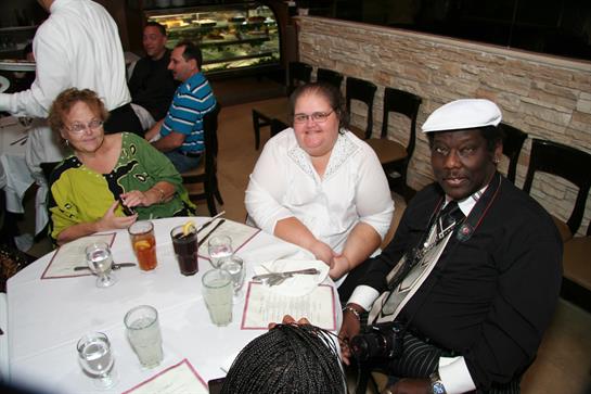 A group of friends sits around a table enjoying a meal and drinks at a local restaurant.