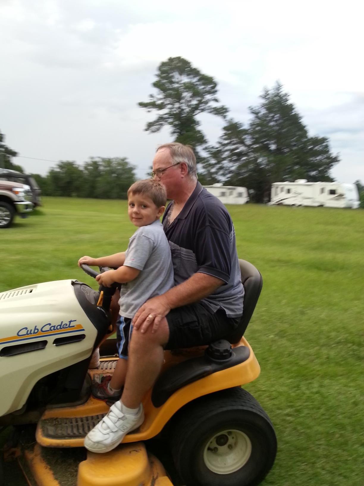 A man and boy on a lawnmower