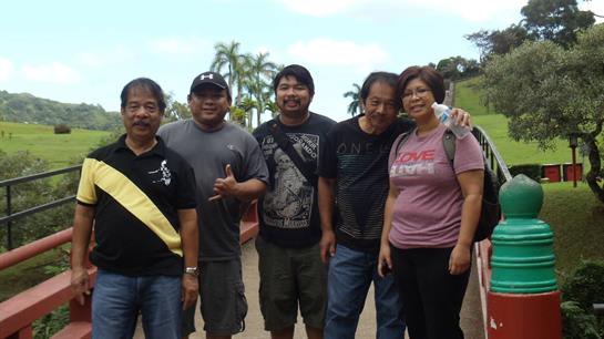 Friends gather together smiling under a bright sky with palm trees in the background.