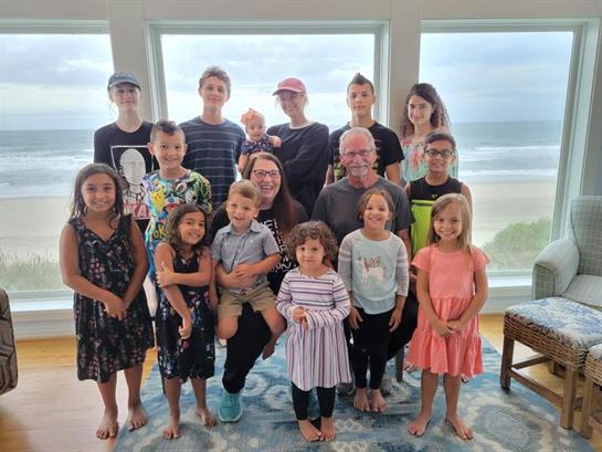 A group of family members poses playfully by a large window overlooking the beach.