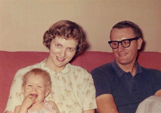 A joyful family smiles together in a cozy living room, radiating love and happiness.