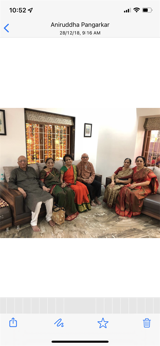 Relatives sit together on a sofa, enjoying warm company in a well-decorated living space.