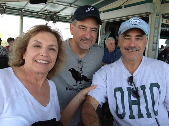 Three friends share smiles while enjoying their time on a boat, likely during summer.