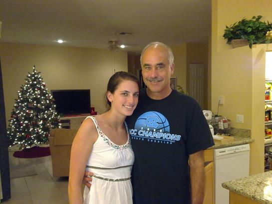 A man and a woman share a joyful moment in a brightly lit living room adorned for the holidays.