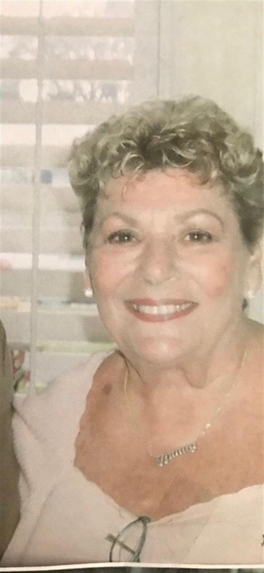 A cheerful woman with curly hair smiles brightly in a cozy indoor space while socializing.