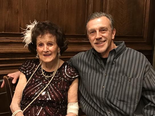 Two individuals share joyful smiles while dressed elegantly for a special family occasion.