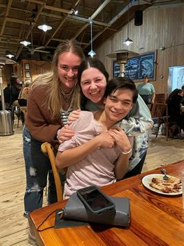 Three friends gather at a cafe, sharing a joyful moment and enjoying tasty treats together.