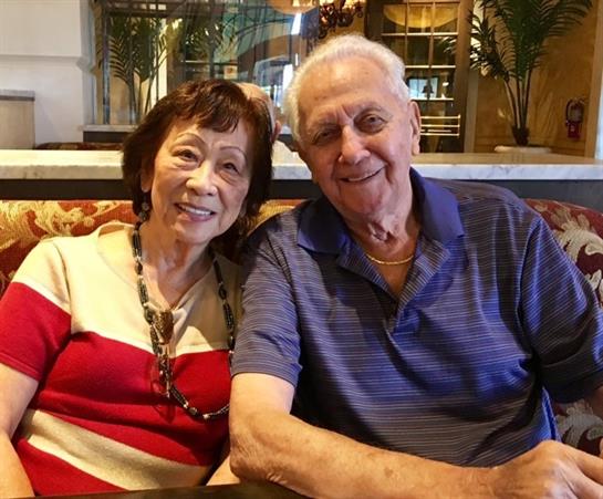 Elderly couple smiles happily while sitting together in a cafe, sharing a joyful moment.