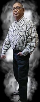 A man showcases classic cowboy fashion with a plaid shirt and jeans in a natural environment.