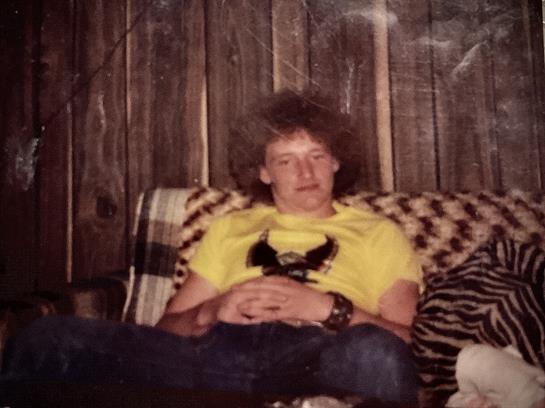 In a cozy space, a young man relaxes on a unique couch with friends.