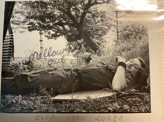 A soldier relaxes on the grass near a river, enjoying a moment of calm in Korea.
