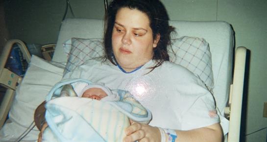 Mother lovingly cradles her newborn baby while resting in a hospital bed post-delivery.
