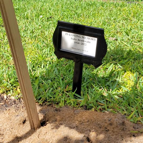 A grave marker displays the name and years of a historical figure surrounded by lush grass.