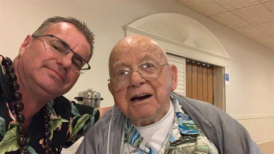 Two men share a cheerful moment together at a community gathering, dressed in bright shirts.