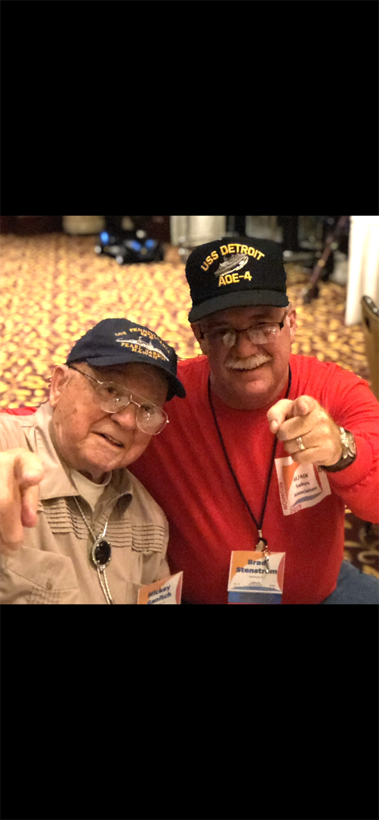 Two veterans enjoy their time at a reunion, reminiscing and sharing stories with smiles.