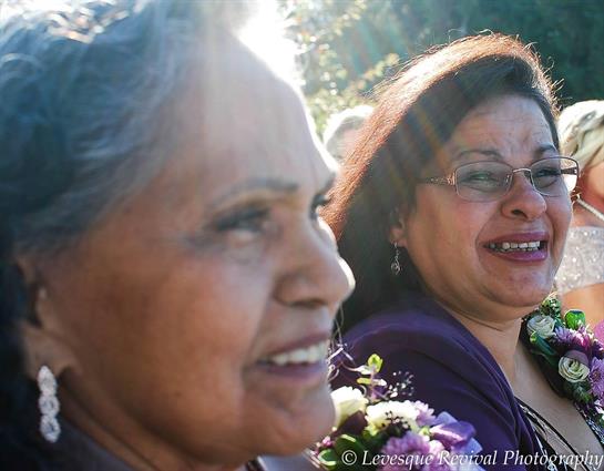Two smiling women enjoy each other's company at a joyful outdoor event in daylight.