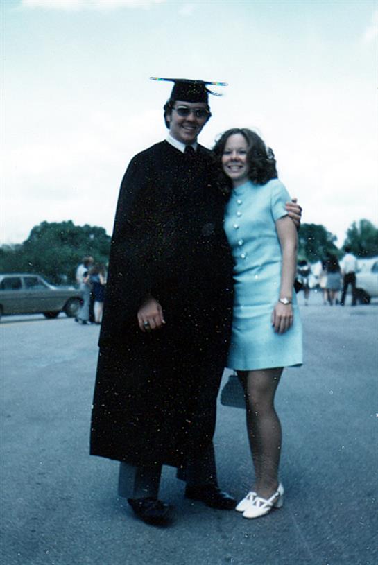 Graduates in gowns joyfully pose outside, celebrating achievements with friends.