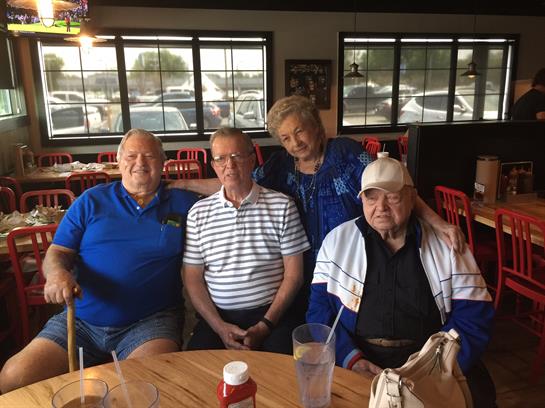 Friends relax together at a restaurant, sharing laughter and conversation over drinks and food.