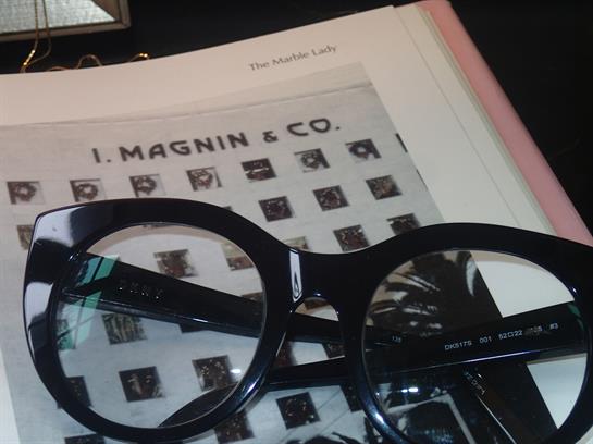 Black glasses sit atop a document showcasing I Magnin and Co's history and images.