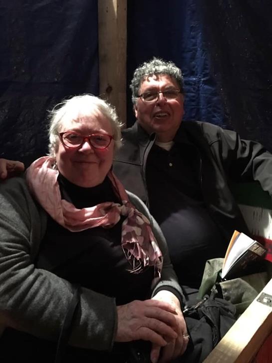 Two adults share smiles and engage in conversation at a relaxed indoor gathering.