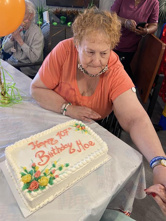 Family and friends gather to celebrate Brittany and Noe's birthday with a cake and laughter.