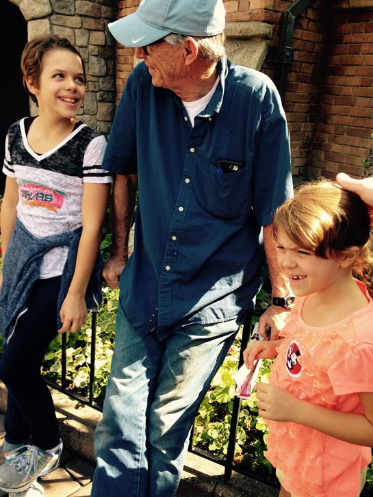 Two children smile and chat with an older man, enjoying a vibrant day in the park full of laughter.