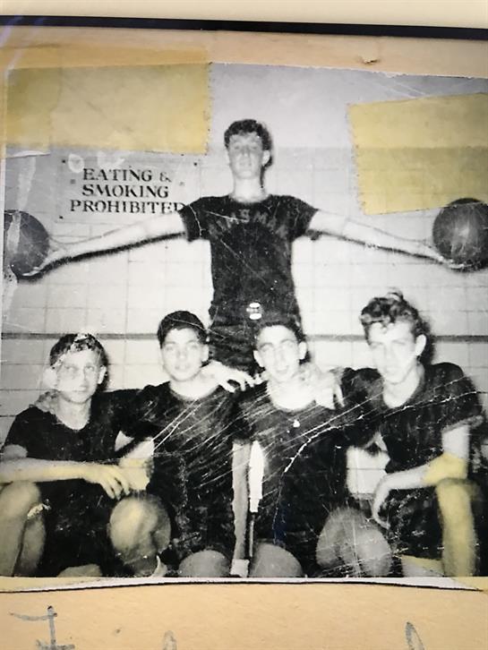 Five young athletes in matching black shirts gather for a group photo in a gym.