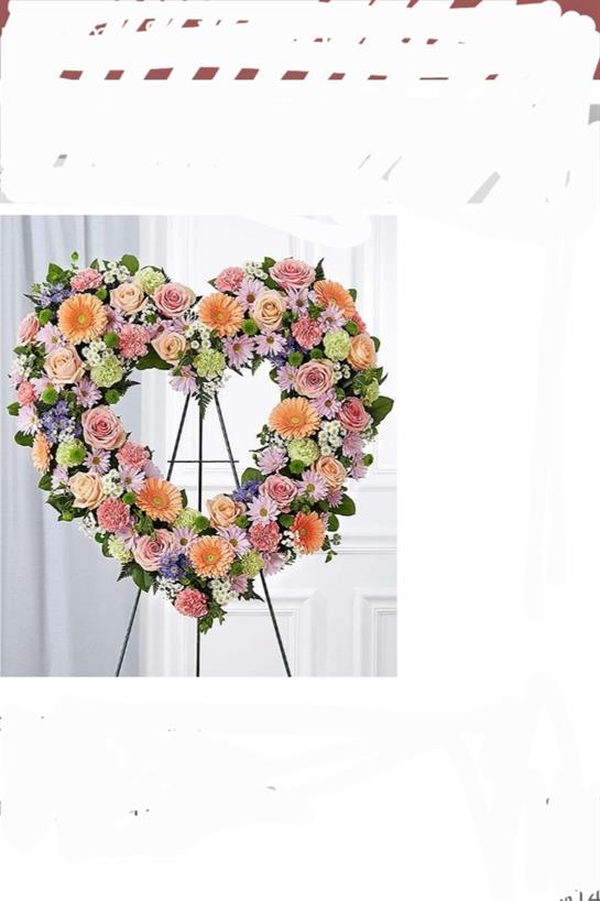 A heart-shaped flower arrangement features colorful blooms, perfect for special events or tributes.