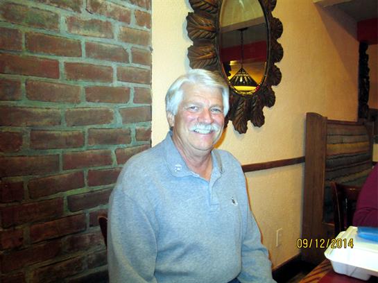 Gentleman smiles while enjoying a meal in a warm, inviting dining environment.