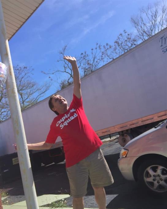 A man in a bright shirt reaches for something in a lively outdoor setting.