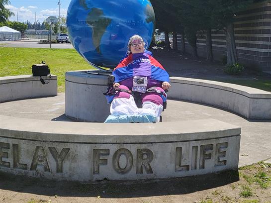 A person dressed in colorful attire promotes a message of unity at a park monument.