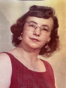A woman showcases her unique style with curly hair and glasses while wearing a vibrant red dress.