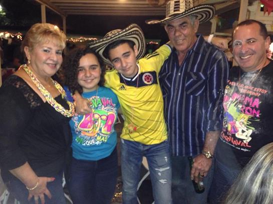 Four people celebrate joyfully in traditional Colombian hats and colorful outfits.