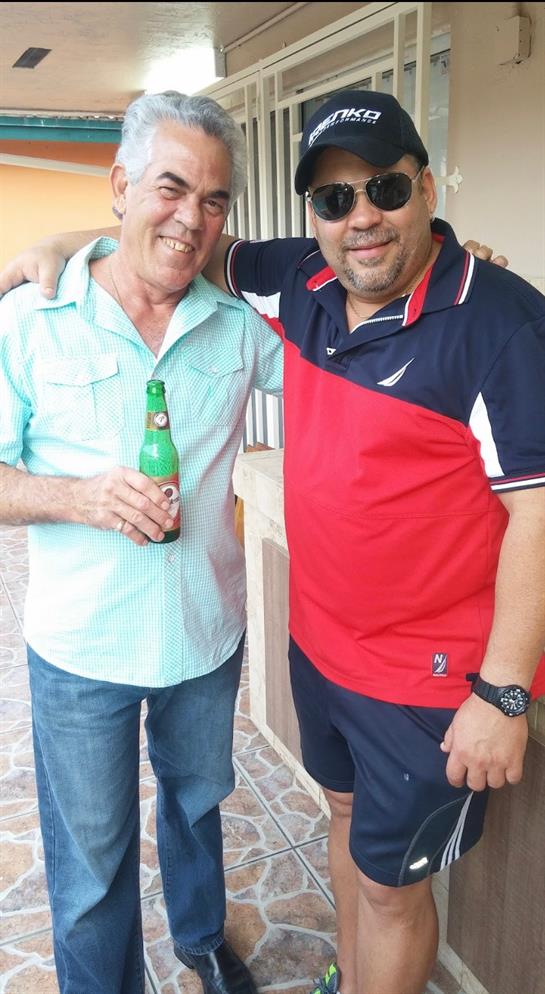 Two friends share a joyful moment while holding drinks at a casual gathering during the day.