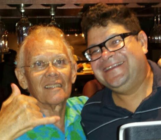 Two smiling men pose together, enjoying their time at a lively gathering in a vibrant atmosphere.