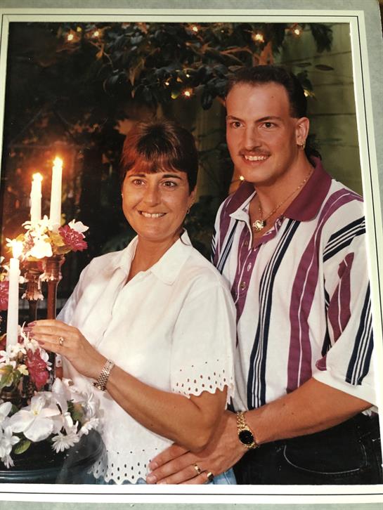 A couple smiles with flowers by lit candles, savoring their special evening together.