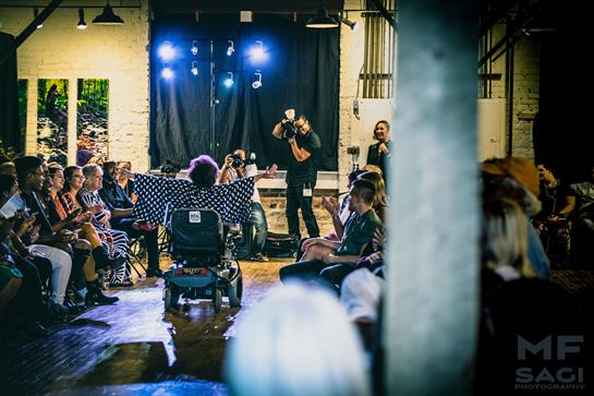 Audience enjoys a live performance in a cozy space with bright stage lights.