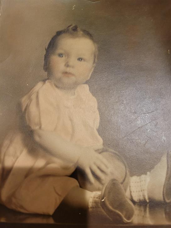 A child sits on someone’s lap, gazing thoughtfully—capturing a nostalgic moment.