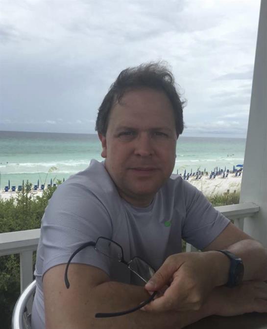 A person relaxes on a porch, enjoying the ocean view as clouds roll in.