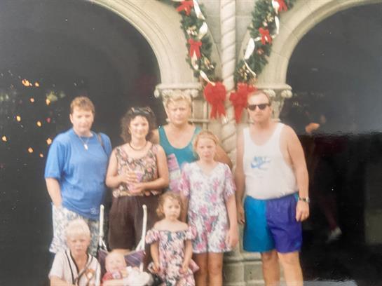 A group of seven people poses together in front of a castle adorned with holiday decorations.