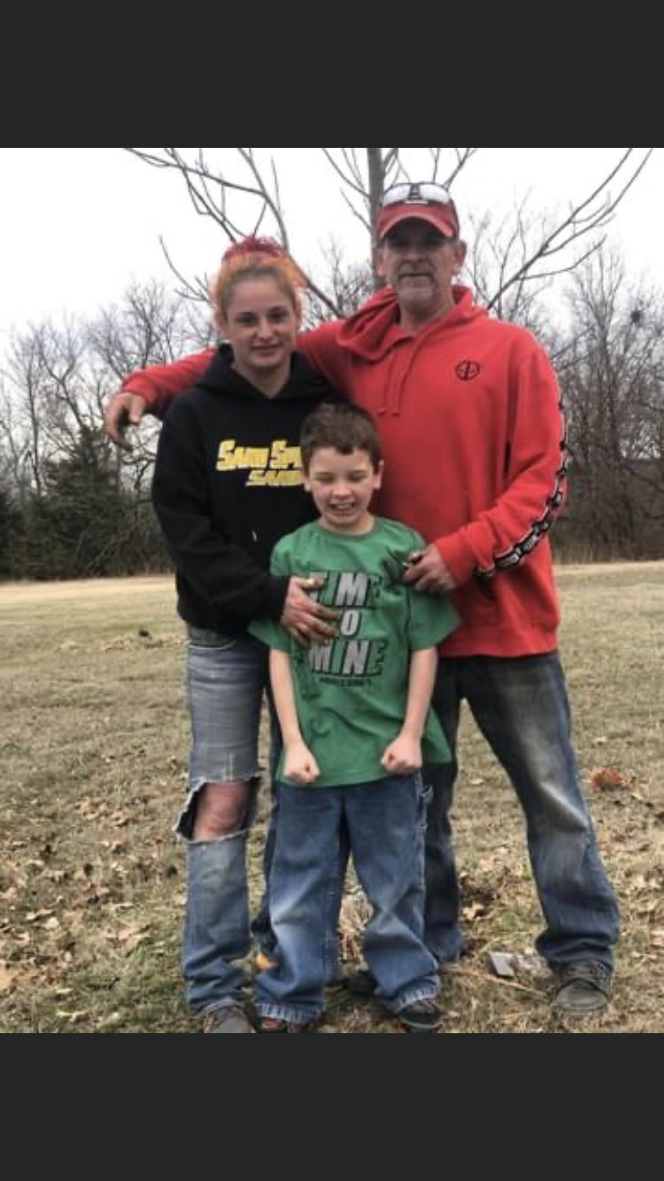 A family stands together outside, smiling warmly while enjoying their time in winter.
