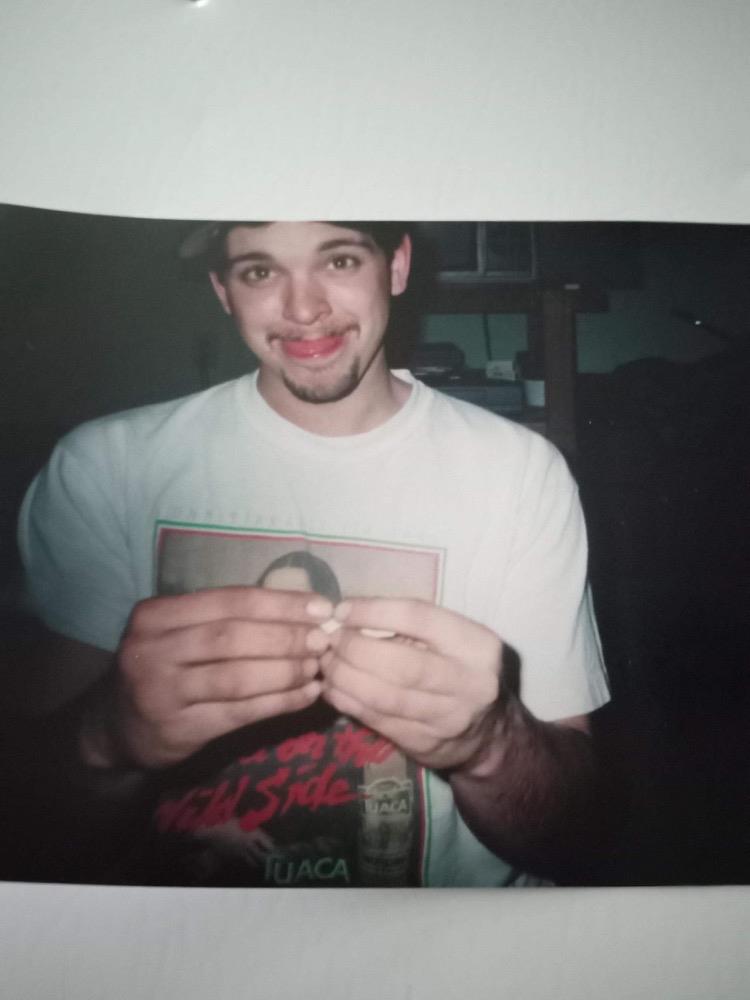 Individual smiles while holding a magazine in a cozy, low-light setting during an evening event.