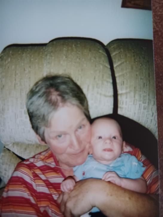 A grandmother lovingly cradles her happy grandchild in a warm, inviting living room.