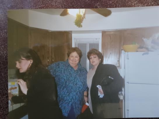 Three women enjoy a lively conversation in a warm kitchen setting.