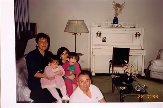 Adults and children sit together in a warm living room, sharing smiles and laughter.