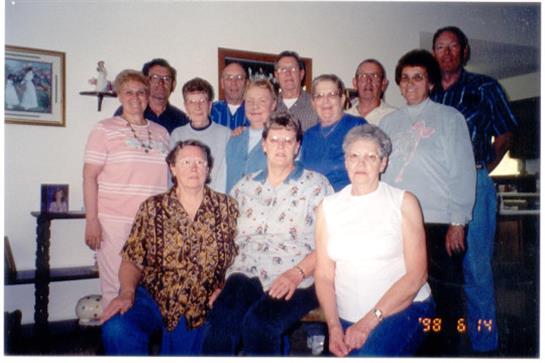 A diverse group of friends poses together in a cozy living room during the late 1990s.