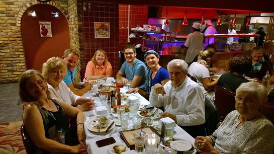 Friends gather at a restaurant, sharing laughter and food around a table filled with plates.
