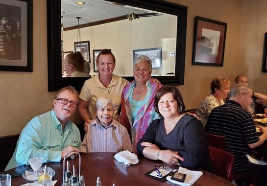 Five family members enjoy a cheerful reunion at a restaurant, celebrating the moment together.